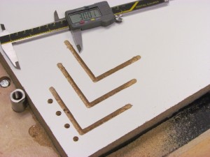 My 1st generation method of calibrating the machine to the workpiece involved milling an "L" shaped dado and measuring the distance from the shoulder to the edge of the sheet. By adjusting the prox switch values and repeating the process, I could get accuracy to within a few thousands of an inch.